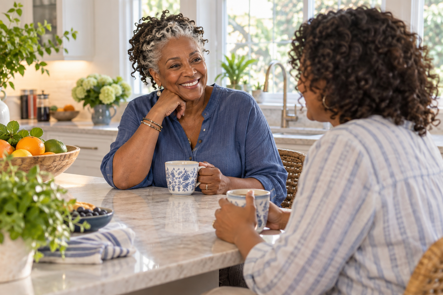 An older adult sharing a conversation over tea in a bright kitchen